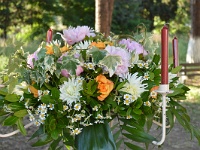 κατασκευή λουλουδιών με ροζ παιόνιες, πορτοκαλί τριαντάφυλλα, λευκή ντάλια και χαμομήλι στο μεταλλικό κηροπήγιο της νυφικής λαμπάδας
