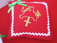 ο σταυρός της μικρής Μαρκέλλας τοποθετημένος σε κόκκινο μαξιλαράκι με πράσινο φιογκάκι