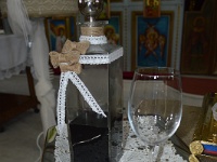 το μπουκάλι και το ποτήρι της στέψης διακοσμημένα με πλεκτή κορδέλα και φιογκάκια λινάτσας