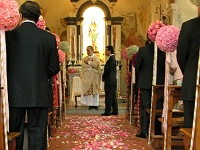 εσωτερικός διάδρομος εκκλησίας με κατασκευές απο μπάλες λουλουδιών και πολύχρωμα ροδοπέταλα πάνω στο χαλί που περπάτησε το ζευγάρι
